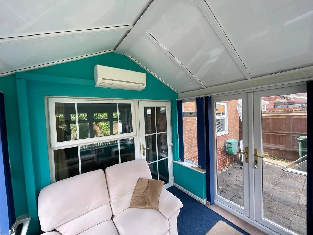 Two-seater sofa in a snug conservatory sitting area under a solid white roof