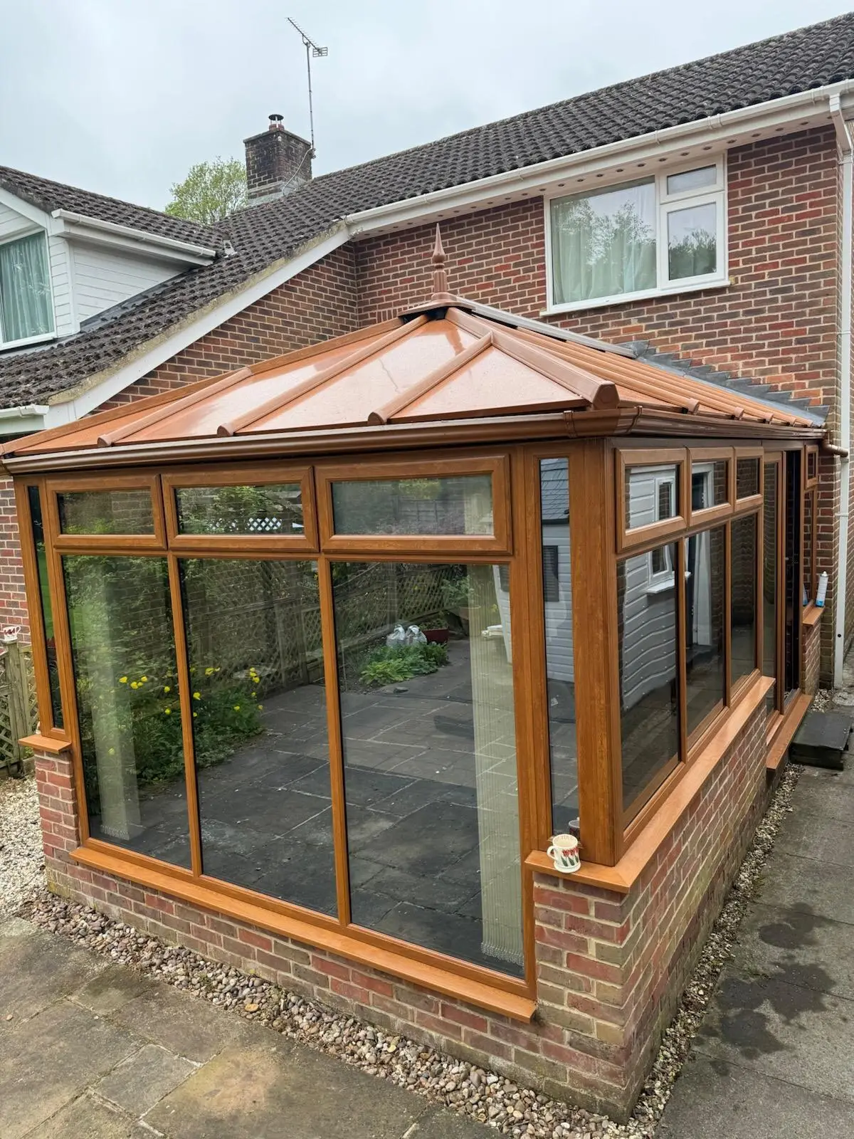 Copper-coloured panel roof topping an oak-effect conservatory, seen from the side