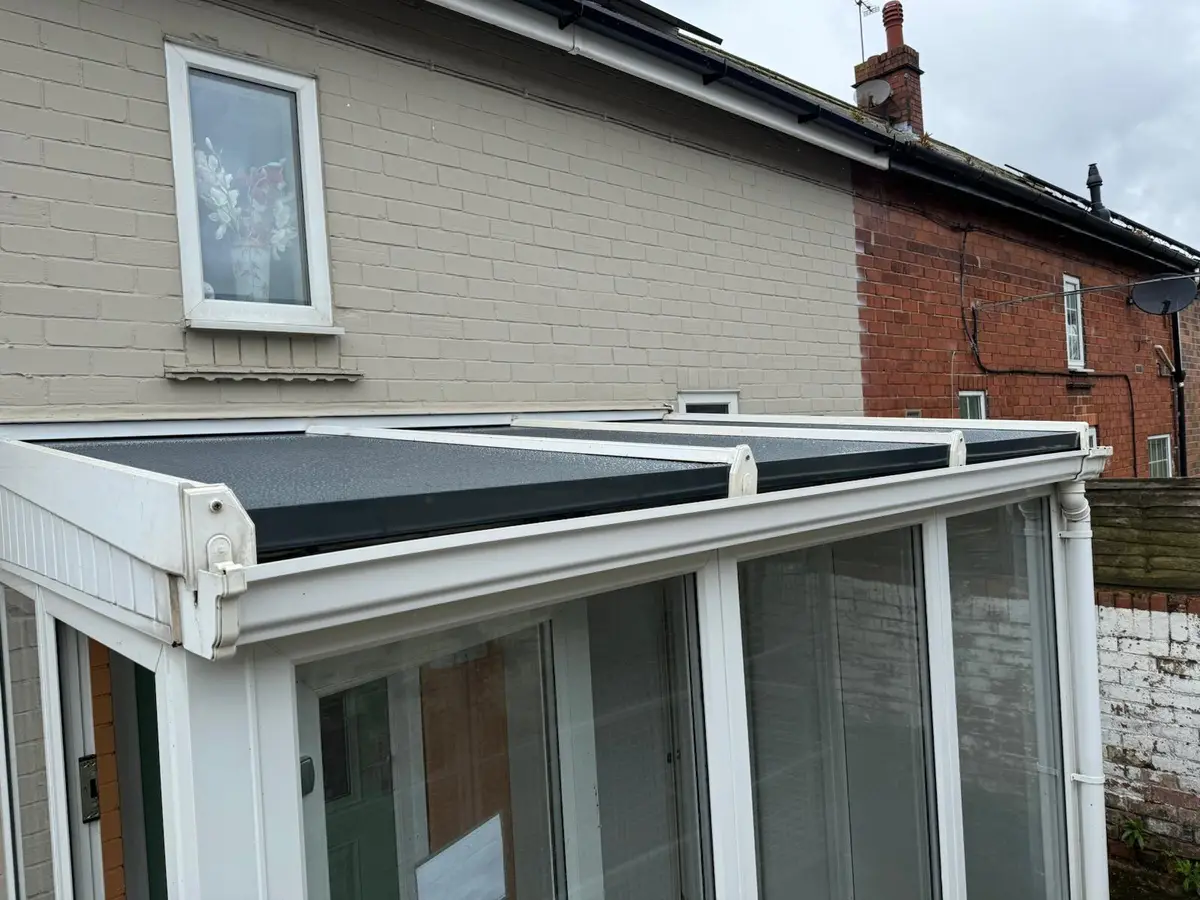 White glazing bars holding new dark grey insulated panels on a lean-to conservatory