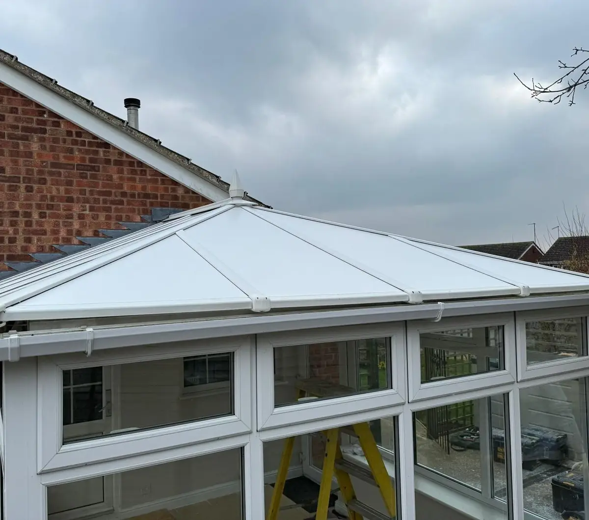 Completed white insulated roof on a conservatory next to a brick bungalow