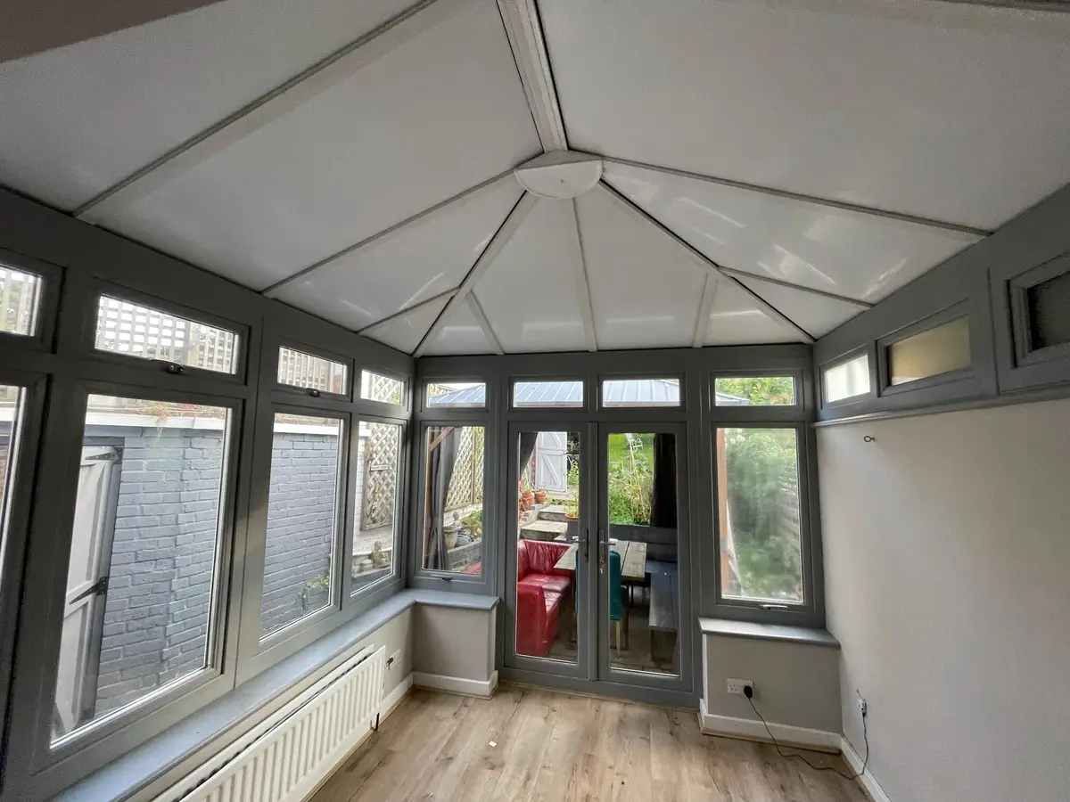View towards the French doors beneath a completed insulated roof in a grey conservatory