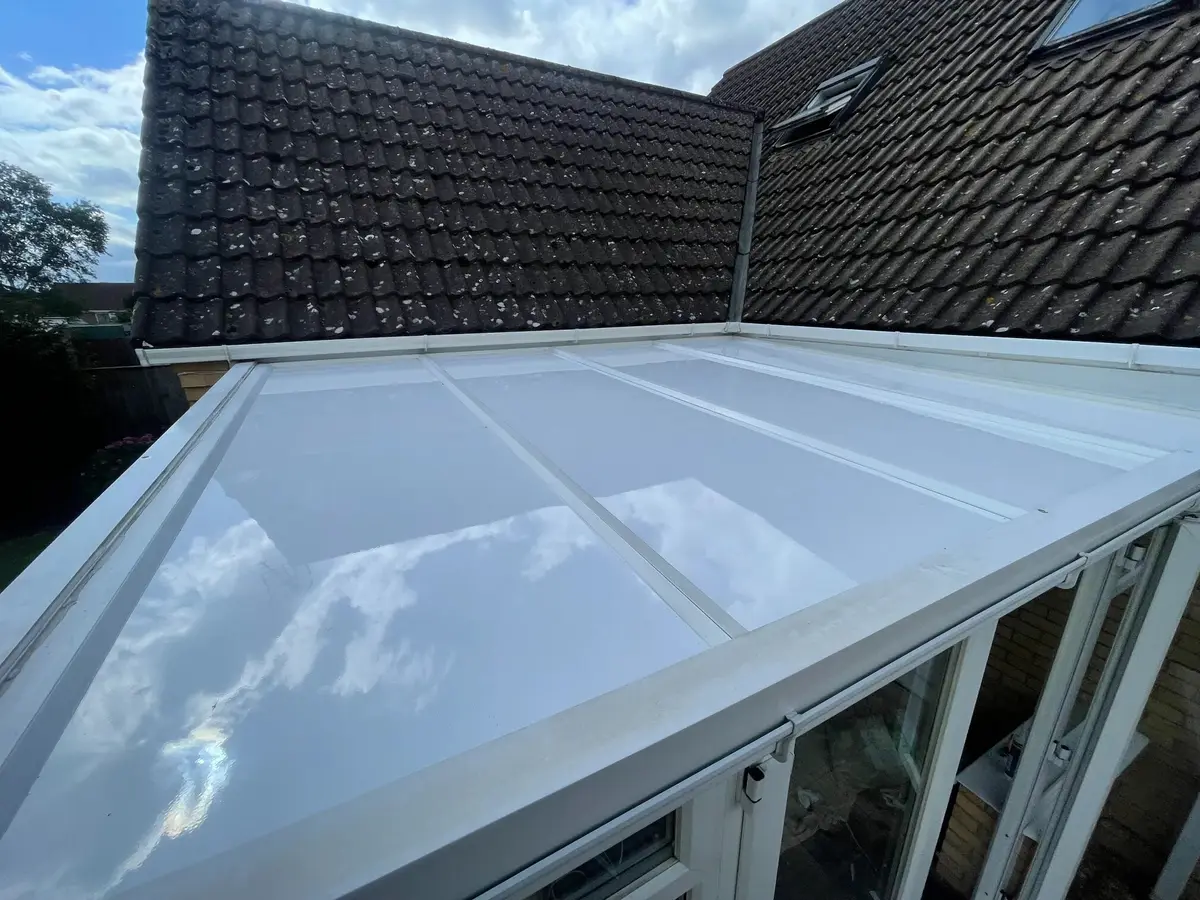 Elevated view down a white insulated lean-to roof next to the pitched roof of the house