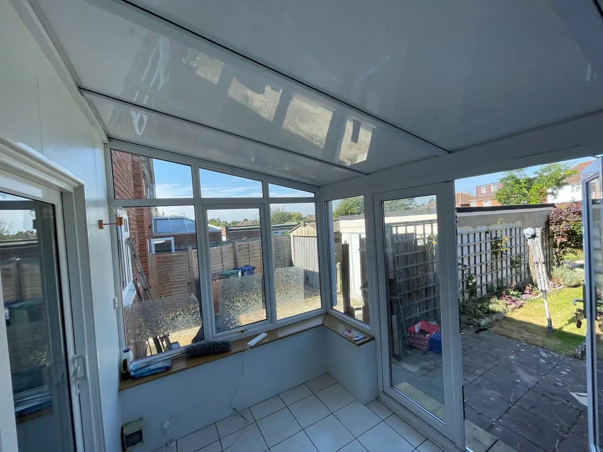 Pale ceramic flooring under a white insulated ceiling in a lean-to conservatory