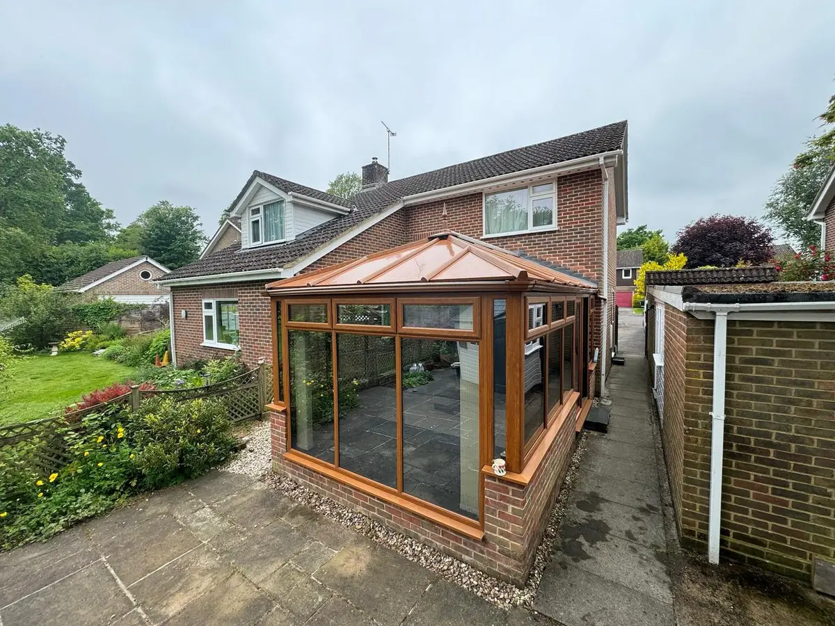 Garden-side oak-effect conservatory now finished with copper-coloured insulated roof panels