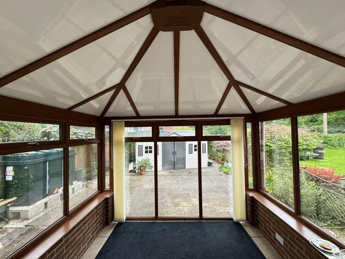 White insulated ceiling panels set between oak-effect rafters in a conservatory