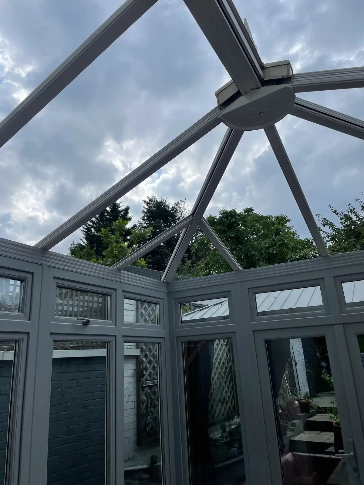 Bare rafters of a conservatory roof open to the sky, prepared for insulated panels