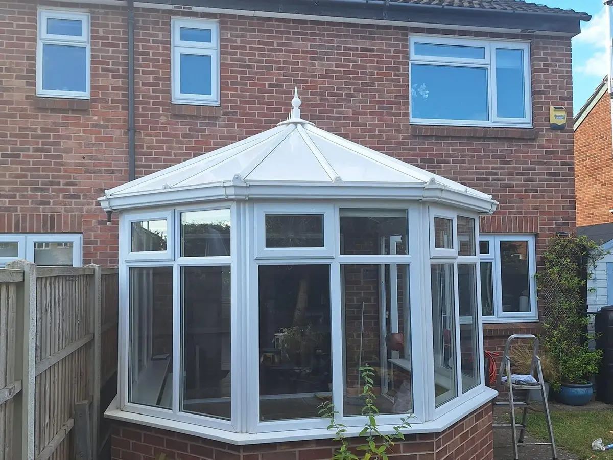 Whole Victorian conservatory, newly roofed in white insulated panels, at the rear of a brick home