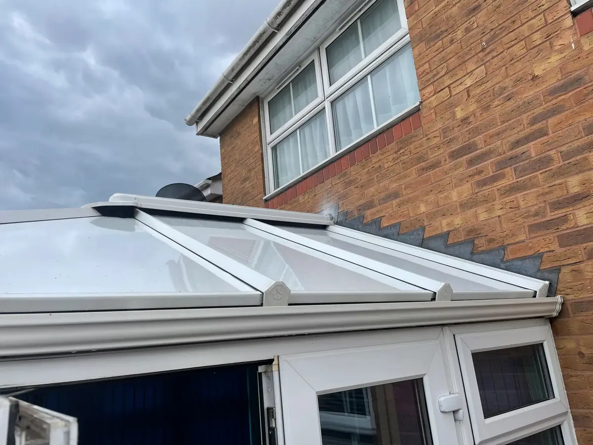 Neat junction where white insulated roof panels meet the house's brick wall