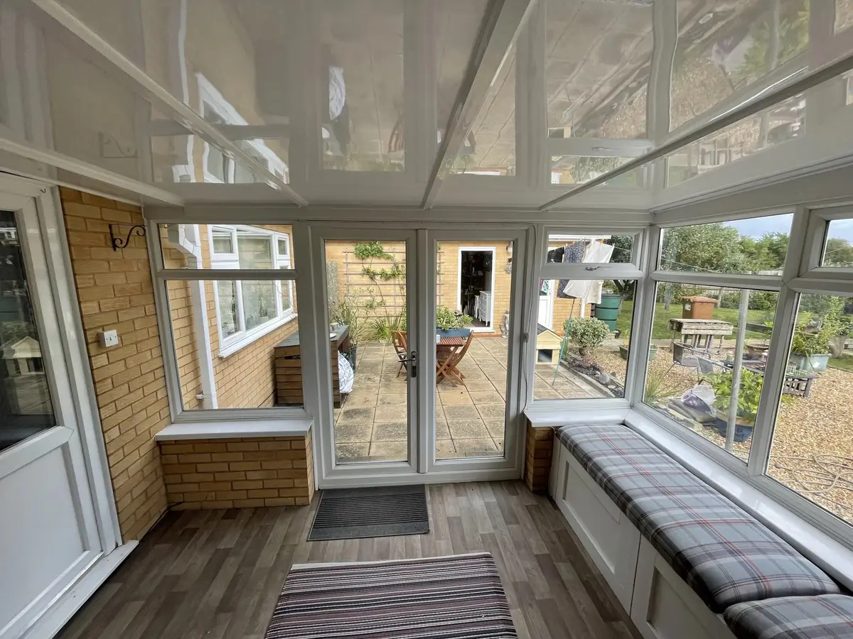 Glossy white insulated ceiling over fitted window seats in a conservatory